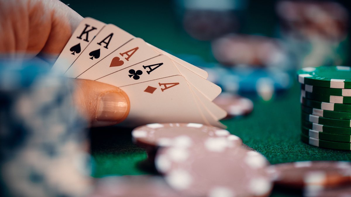 Main de poker et piles de jetons sur tapis vert